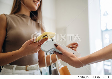 Detailed close up view. Woman is paying for clothes, in the retail store Detailed close up view. Woman is paying for clothes, in the retail store 133616961