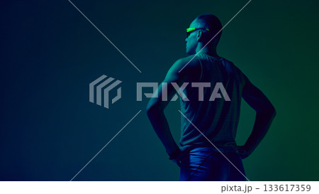 Athlete standing hands on hips in blue-green neon studio lighting Athlete standing hands on hips in blue-green neon studio lighting 133617359