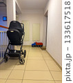 Baby stroller and toy truck left in an apartment hallway with tile floor and stairway rail. 133617518