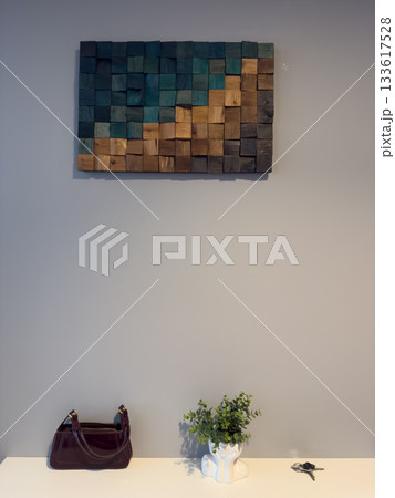 Minimalist entryway with handbag, keys, plant in sculptural vase and wooden wall decor. Concept Minimalist Home Decor Minimalist entryway with handbag, keys, plant in sculptural vase and wooden wall decor. Concept Minimalist Home Decor 133617528