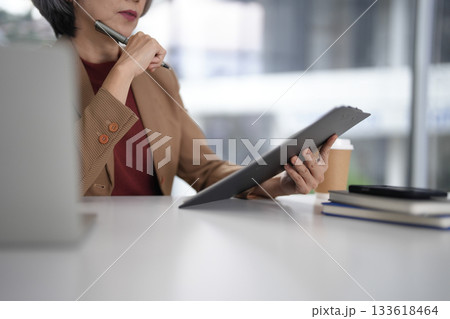 Asian senior executive businesswoman thinking reviewing important documents strategizing corporate success in modern office environment global leadership planning financial growth Asian senior executive businesswoman thinking reviewing important documents strategizing corporate success in modern office environment global leadership planning financial growth 133618464