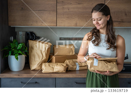 Woman holding a labeled grocery bag with the word Recept, meaning recipe in another language. Concept of convenient meal kit delivery with pre-portioned, ready-to-cook ingredients. 133619719