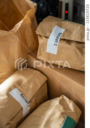 Close-up of brown paper bags with meal kits labeled Recept or Recipe. Subscription-based food delivery sorted by recipes. 133619720