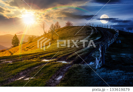 wooden fence near country dirt road through the grassy hill in spring. day and night time change concept. beautiful scenery of mountainous rural area with sun and moon. harmony and progress calendar wooden fence near country dirt road through the grassy hill in spring. day and night time change concept. beautiful scenery of mountainous rural area with sun and moon. harmony and progress calendar 133619879