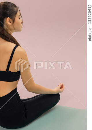 Woman sitting in yoga meditation pose on mat, practicing yoga breathing and relaxation, wellness routine and mindful fitness for calm balance and healthy lifestyle. 133620410