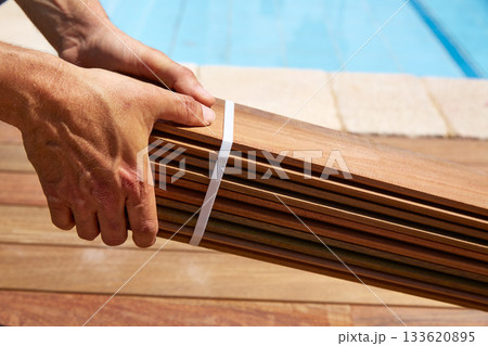 Ipe deck installation carpenter hands holding wood Ipe deck installation carpenter hands holding wood 133620895