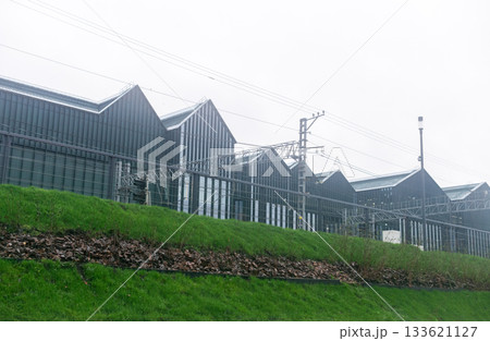 Foggy view of a modern industrial building behind the railway embankment 133621127