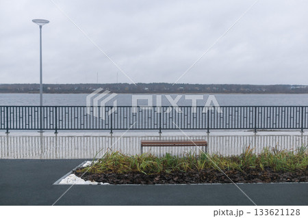 Bench on the embankment of the lake in cloudy weather. Bench on the embankment of the lake in cloudy weather. 133621128