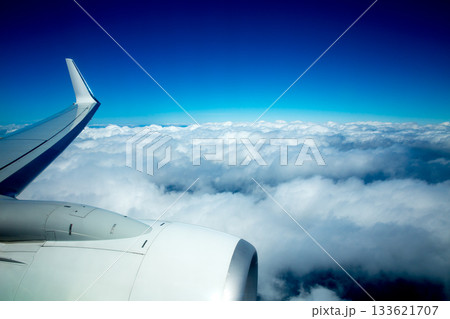 Airplane wing flying over fluffy clouds in blue sky 133621707