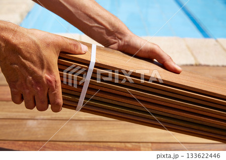 Ipe deck installation carpenter hands holding wood Ipe deck installation carpenter hands holding wood 133622446