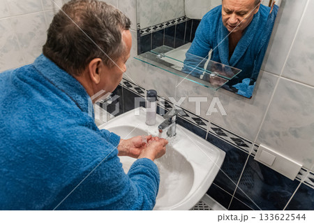 Man washing hands in bathroom in front of mirror. Morning shaving routine. Back view. 133622544