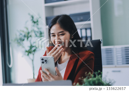 Smiling relaxed young woman sitting on couch using cell phone technology, happy lady holding smartphone, scrolling, looking at cellphone enjoying doing online ecommerce shopping in mobile apps. Smiling relaxed young woman sitting on couch using cell phone technology, happy lady holding smartphone, scrolling, looking at cellphone enjoying doing online ecommerce shopping in mobile apps. 133622657