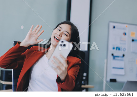 Serious charming woman using smartphone while working with laptop 133622661