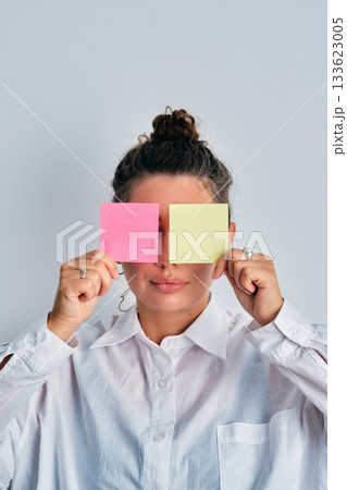 Woman covering eyes with colorful sticky notes Woman covering eyes with colorful sticky notes 133623005