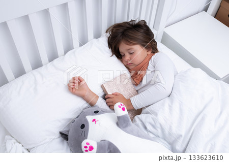 Young caucasian girl sleeping peacefully with stuffed cat in white bed Young caucasian girl sleeping peacefully with stuffed cat in white bed 133623610