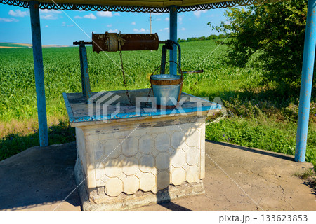 Traditional Manual Water Well Overlooking Bright Green Corn Crops 133623853