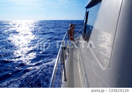 Boat side sailing in blue sea sun reflection Boat side sailing in blue sea sun reflection 133624129