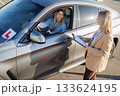 Driving Student Talking with Instructor beside Car during License Exam 133624195