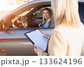Young Learner Driver Adjusting Seatbelt While Instructor Takes Notes 133624196
