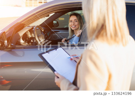 Young Learner Driver Adjusting Seatbelt While Instructor Takes Notes Young Learner Driver Adjusting Seatbelt While Instructor Takes Notes 133624196