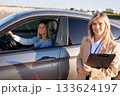 Driving Instructor Standing Near Car with Smiling Student Ready for Exam 133624197