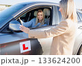 Driving Instructor Checking Exterior Mirrors of Learner Vehicle Before Test 133624200