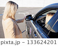 Instructor Adjusting Side Mirror for Student Driver before Driving Lesson 133624201