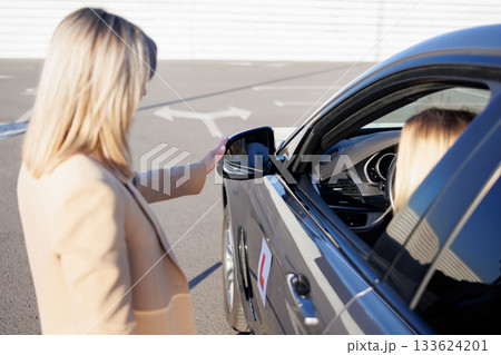 Instructor Adjusting Side Mirror for Student Driver before Driving Lesson Instructor Adjusting Side Mirror for Student Driver before Driving Lesson 133624201