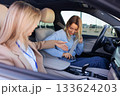 Driving Instructor Teaching Student to Properly Buckle Seatbelt Before Test 133624203