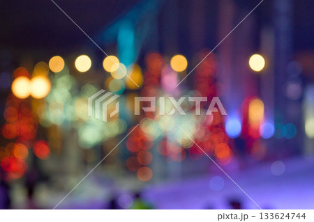 Defocused red, teal, and gold circles shimmer against a dark night scene. A vibrant bokeh field makes a rich, festive background. 133624744
