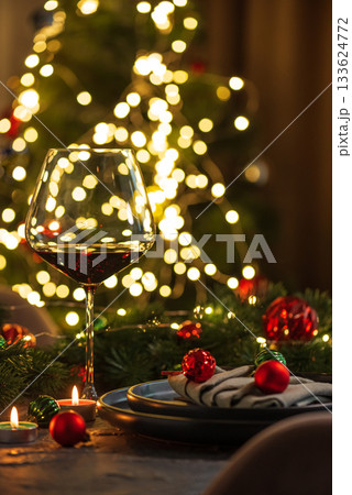 Christmas Table Setting with Wineglasses with Red Wine against Christmas lights Christmas Table Setting with Wineglasses with Red Wine against Christmas lights 133624772