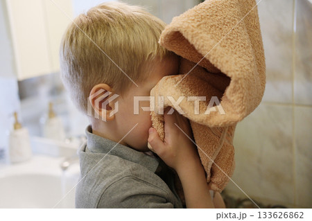 Young boy drying face with soft towel in bathroom Young boy drying face with soft towel in bathroom 133626862