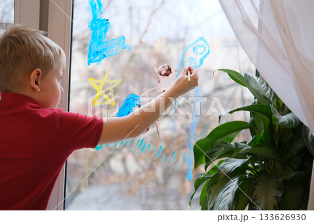 Young boy drawing on window with colorful paint Young boy drawing on window with colorful paint 133626930
