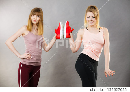 Two women presenting sportswear trainers shoes Two women presenting sportswear trainers shoes 133627033
