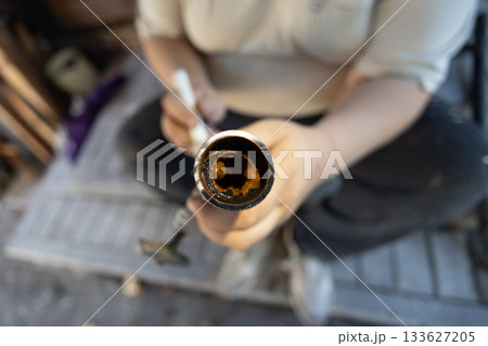 Plumber holding a cut section of an old metal water pipe, revealing severe rust and mineral buildup from corrosion inside, demonstrating the need for plumbing maintenance. Plumber holding a cut section of an old metal water pipe, revealing severe rust and mineral buildup from corrosion inside, demonstrating the need for plumbing maintenance. 133627205
