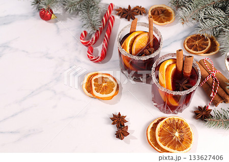 Warming winter drink in the cold season, festive Christmas grog, strong alcoholic or non-alcoholic cocktail on the festive table, mulled wine with spices, star anise, cranberries, orange, apple 133627406