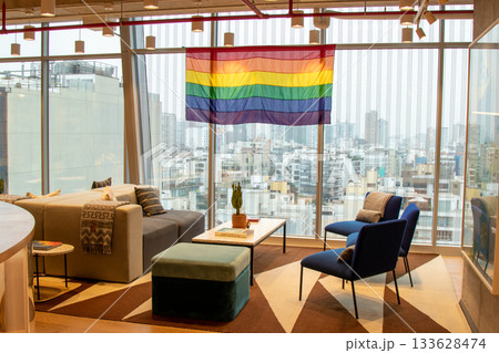 A room with a large window and a rainbow flag hanging from the ceiling 133628474