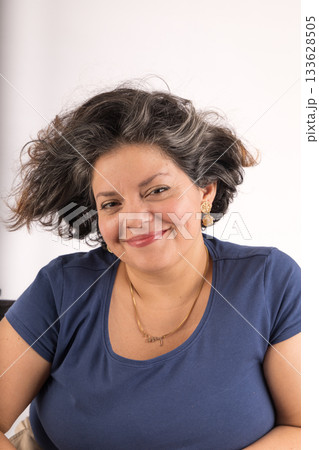 A woman with a blue shirt and a necklace is smiling A woman with a blue shirt and a necklace is smiling 133628505