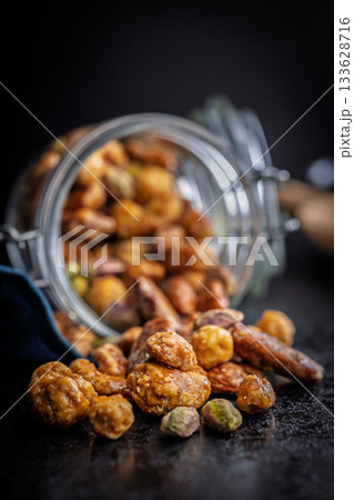 Nuts coated in sugar glaze on black table. Nuts coated in sugar glaze on black table. 133628716
