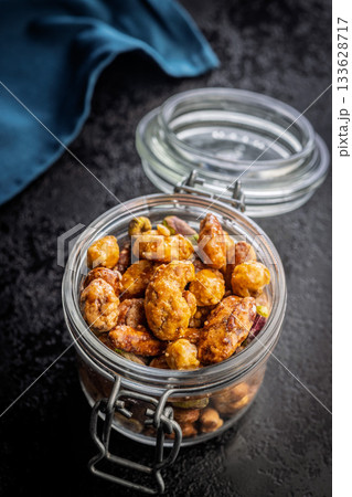 Nuts coated in sugar glaze in jar on black table. Nuts coated in sugar glaze in jar on black table. 133628717