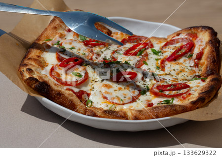 Delicious Neapolitan pizza Margherita close-up. Margarita pizza with tomatoes and paprika. Delicious Neapolitan pizza Margherita close-up. Margarita pizza with tomatoes and paprika. 133629322