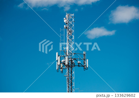 Cellular communication tower with modern antennas and cables against clear blue sky, showing telecom equipment and network infrastructure 133629602