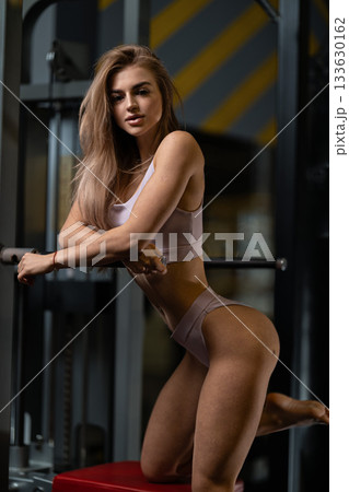 girl shows confidence while near the gravitron machine in a gym setting. She is focused showcasing her strength and fitness in workout clothing. girl shows confidence while near the gravitron machine in a gym setting. She is focused showcasing her strength and fitness in workout clothing. 133630162