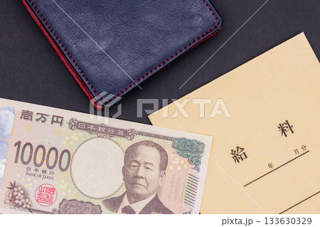 黒い背景に置かれた、給料袋と一万円札と革財布 133630329
