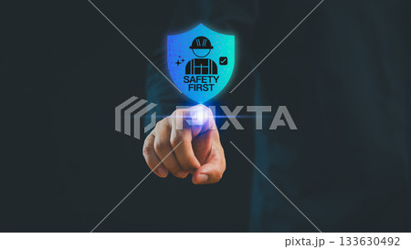 Businessman pointing at a glowing digital shield icon showing Safety First, symbolizing workplace safety, cyber protection, risk management and secure technology. 133630492