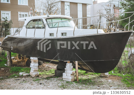 Black boat on wooden blocks in urban backyard setting Black boat on wooden blocks in urban backyard setting 133630552