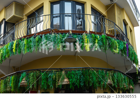 Lush greenery adorning yellow building with curved balcony Lush greenery adorning yellow building with curved balcony 133630555