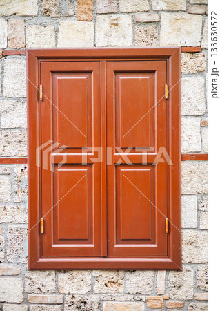 Closed wooden window on stone wall with rustic charm 133630572