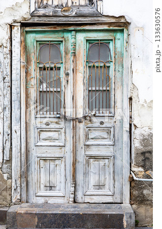Rustic weathered wooden door with metal bars and chain in vintage urban setting Rustic weathered wooden door with metal bars and chain in vintage urban setting 133630576