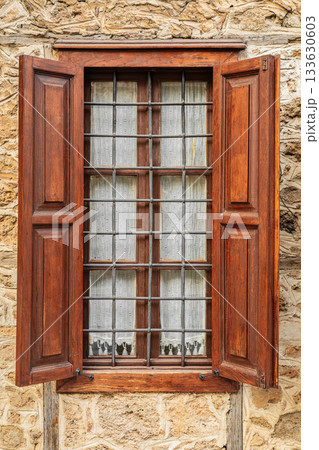 Rustic wooden window with iron bars on stone wall 133630603